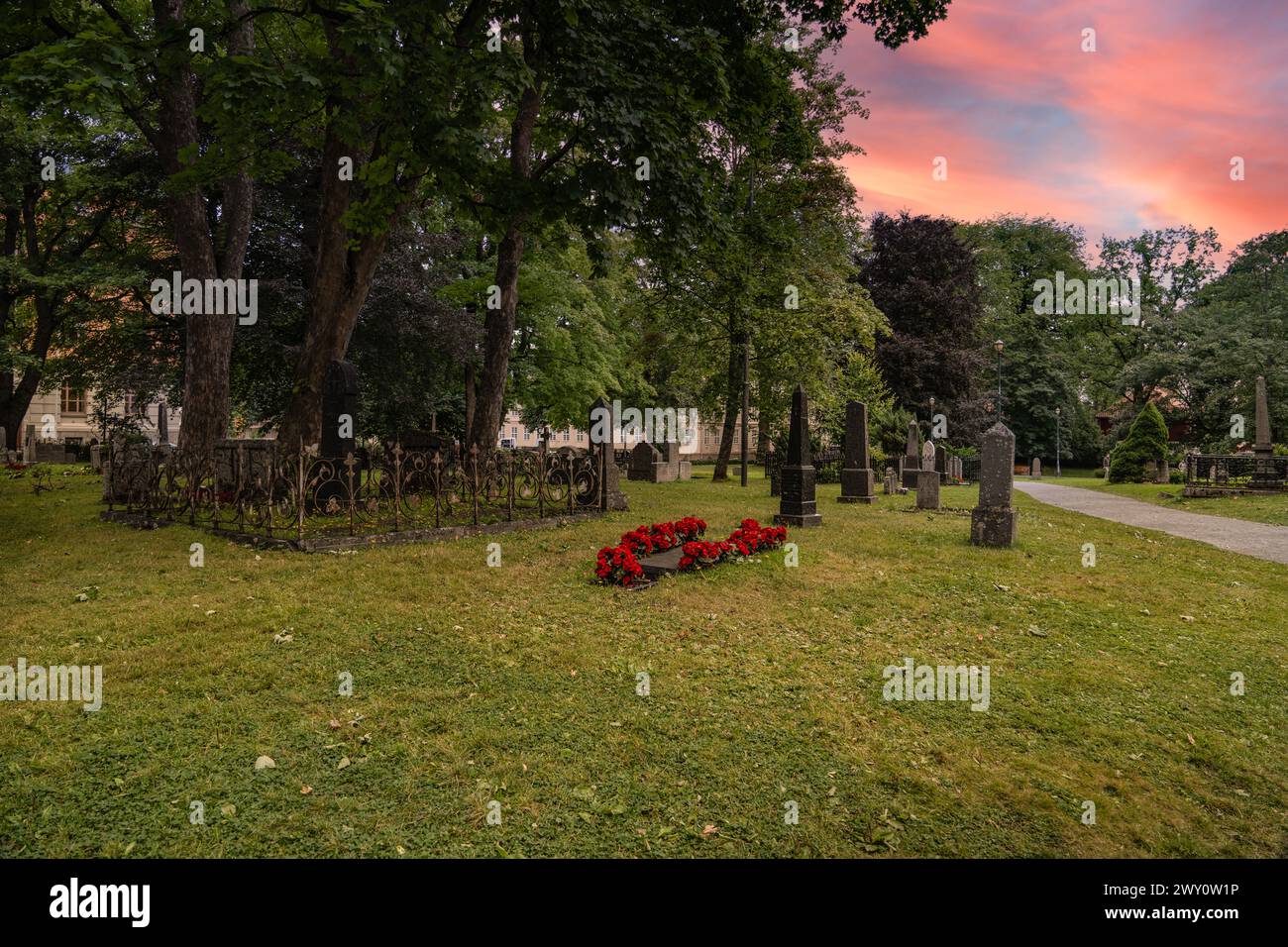 Dusk at Nidaros Cathedral Graveyard in Trondheim Norway. Serene evening at the burial ground with sunset sky casting warm hues over the historic site Stock Photo