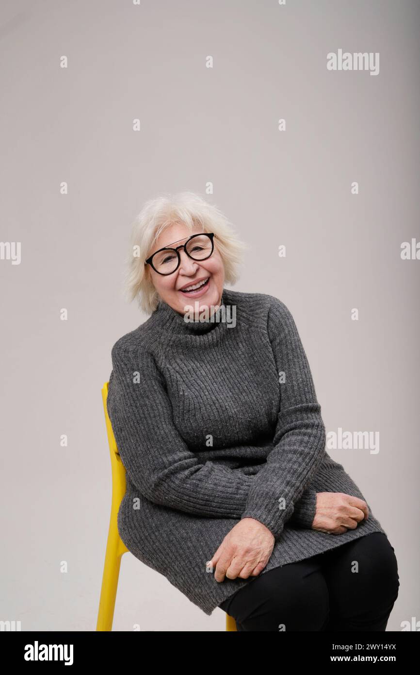 senior woman smiling sitting on chair .looking at camera on clear background Stock Photo