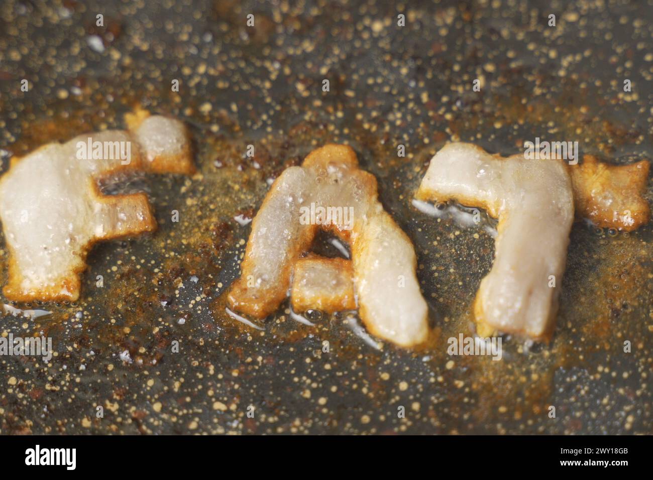 Three cheese letters spell out the word FAT, bubbling and browning as they melt on a hot pan, hinting at the concept of diet and nutrition. Stock Photo