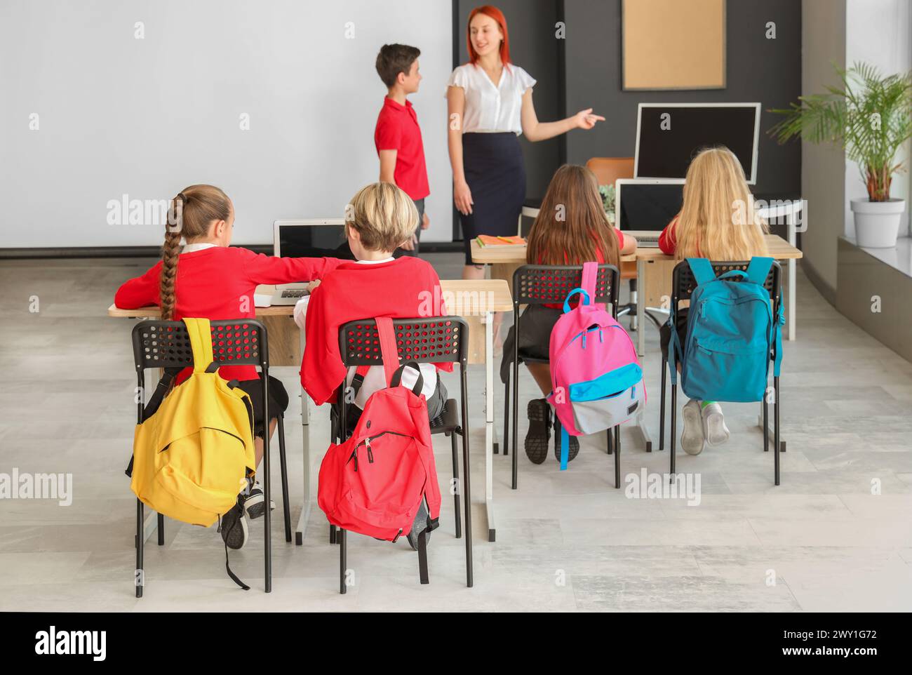 Little children with teacher studying at school computer lab, back view ...