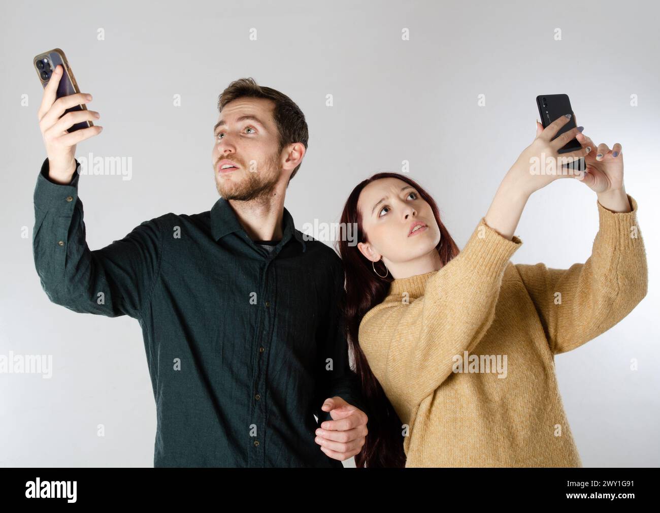 No cell phone network signal. No communication coverage, device contact signal lost. Man and woman search with their smart phones for mobile signal. Stock Photo