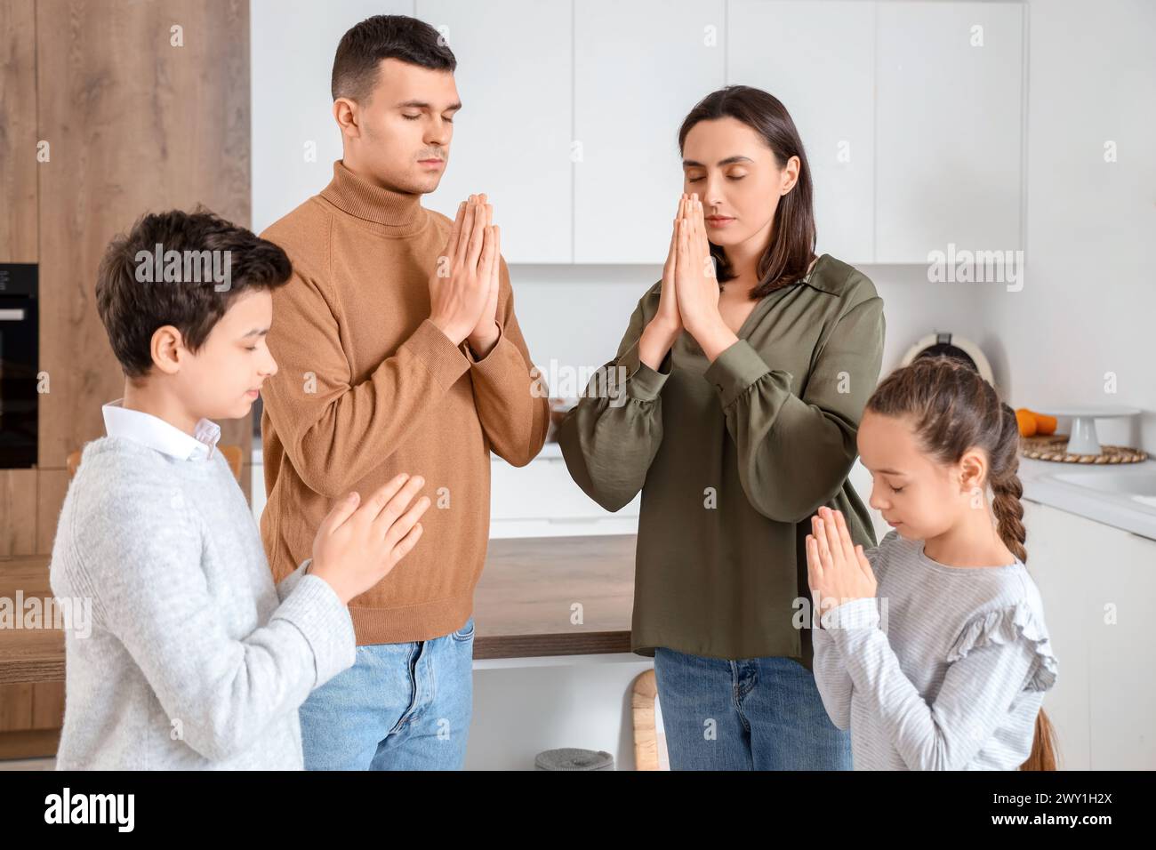 Family praying together in kitchen Stock Photo