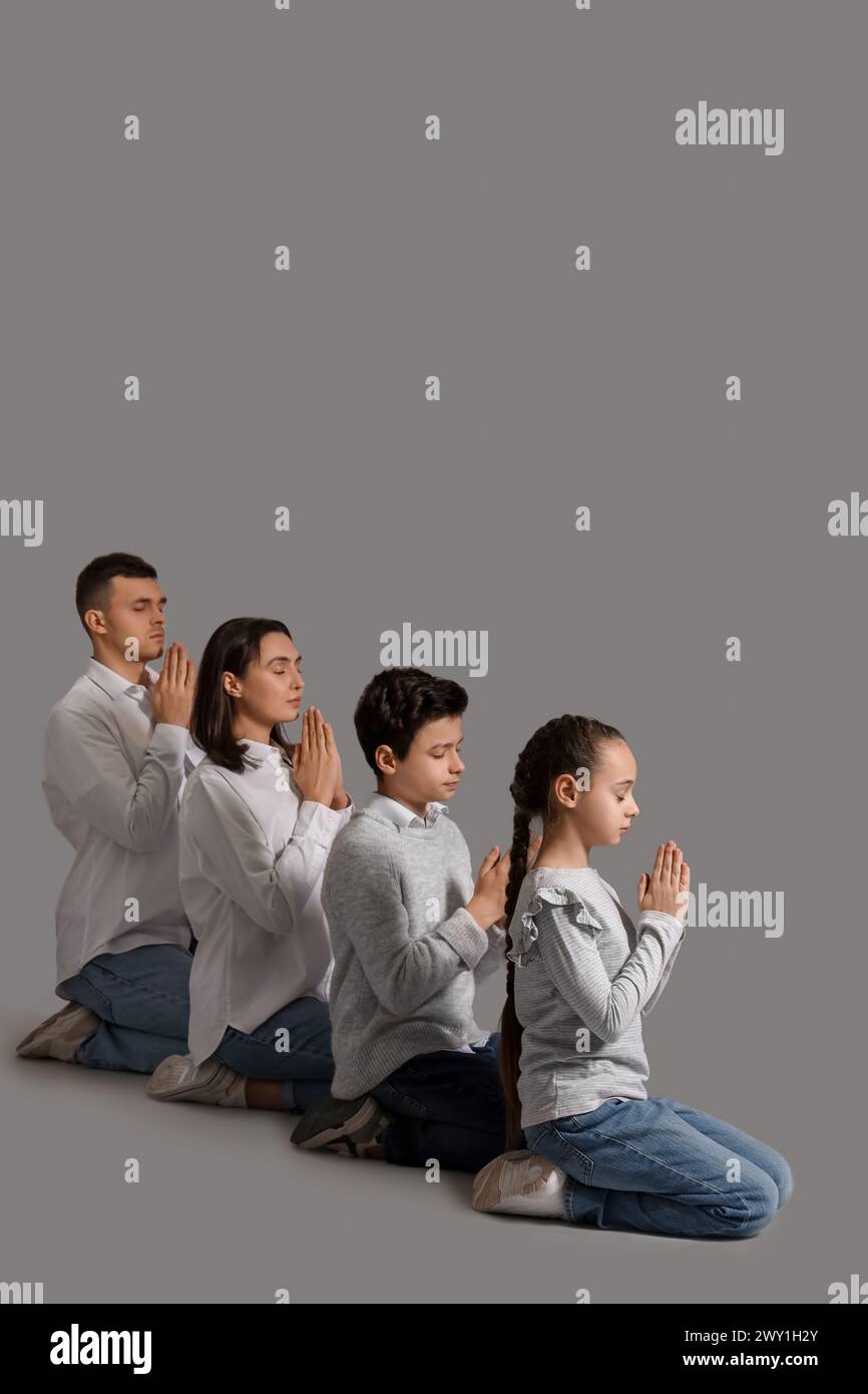 Family praying together on grey background Stock Photo