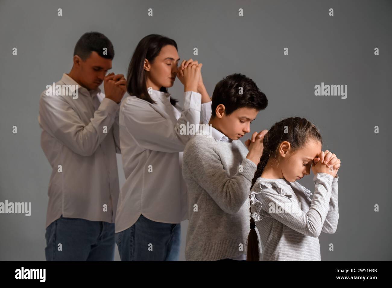 Family praying together on grey background Stock Photo