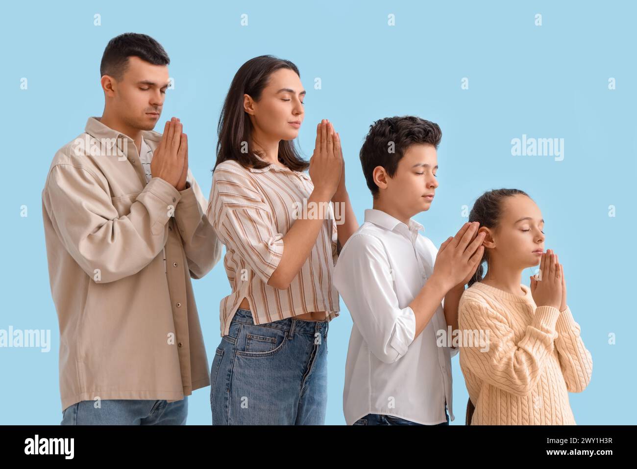 Family praying together on blue background Stock Photo