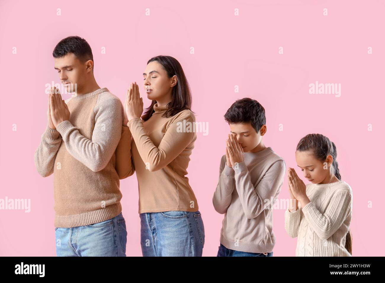 Family praying together on pink background Stock Photo