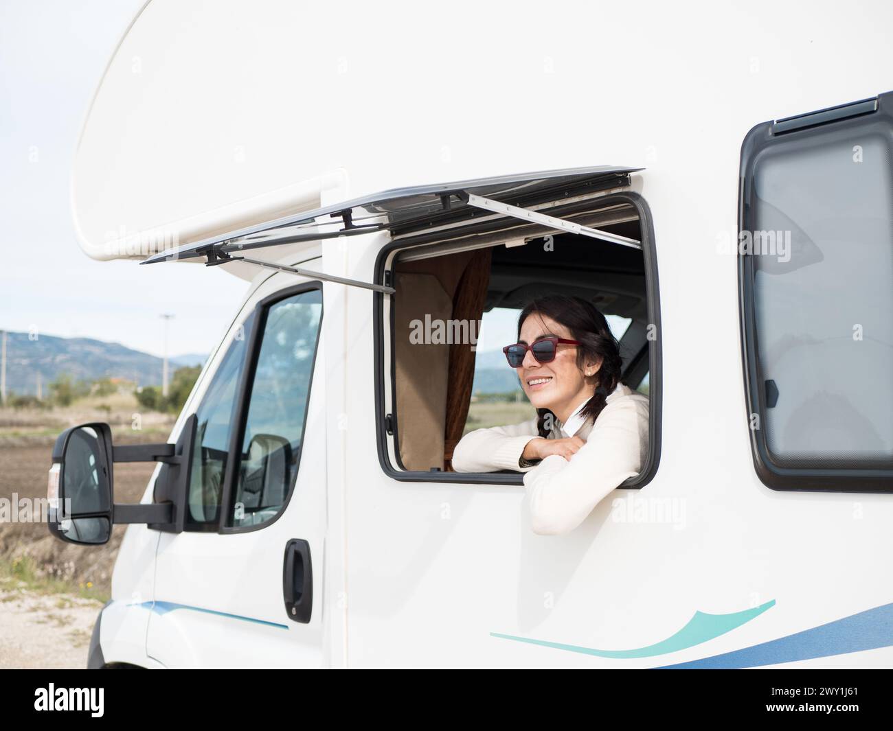 Happy latin woman looking out the motorhome window Stock Photo - Alamy