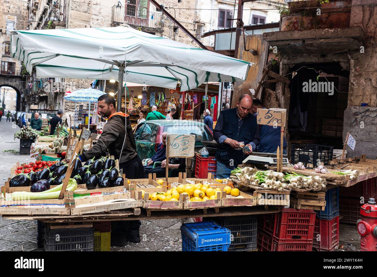 Palermo, Italy - May 13, 2023: Vendors at a fruit and vegetable shop, one of them counting money, in Ballaro Market, street food market in Palermo, Si Stock Photo