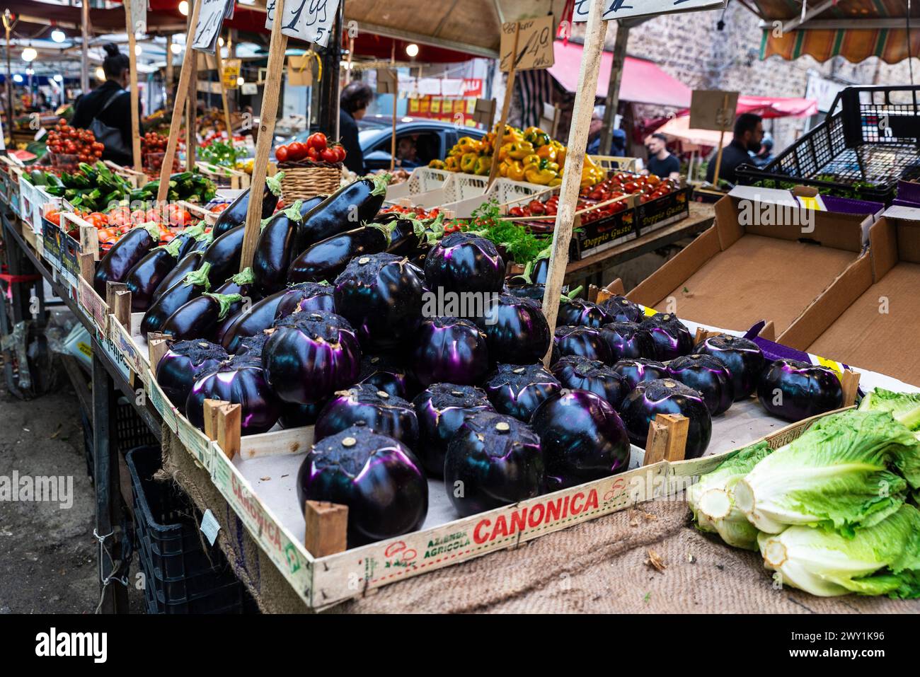 Palermo, Italy - May 13, 2023: Eggplants in a fruit and vegetable shop in Ballaro Market, street food market with people around in Palermo, Sicily, It Stock Photo