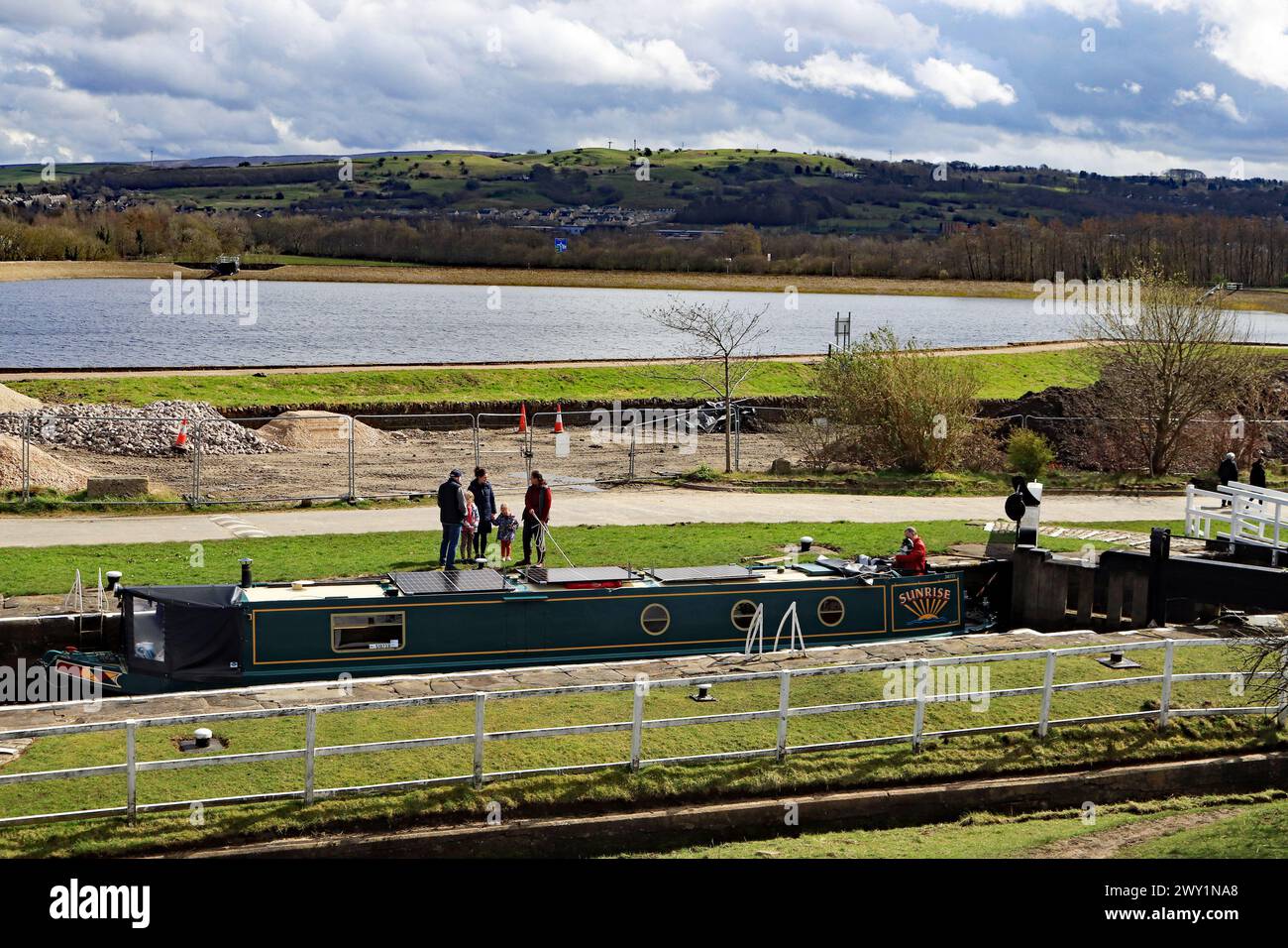 The water in Barrowford reservoir shines in the spring East Lancashire sunshine on Good Friday as a narrowboat rises up through a lock Stock Photo