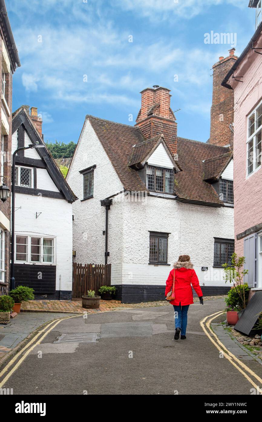 Woman in a red coat walking through the old streets and alleyways of the Shropshire town of Bridgnorth England Stock Photo