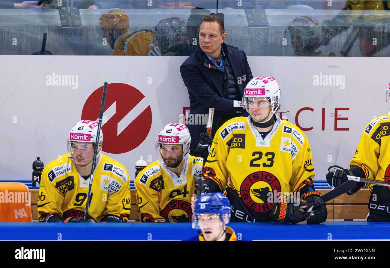Jussi Tapola, head coach SC Bern at work on the players' bench during the game against EV Zug in the Bossard Arena. In front of them sit players #91 F Stock Photo