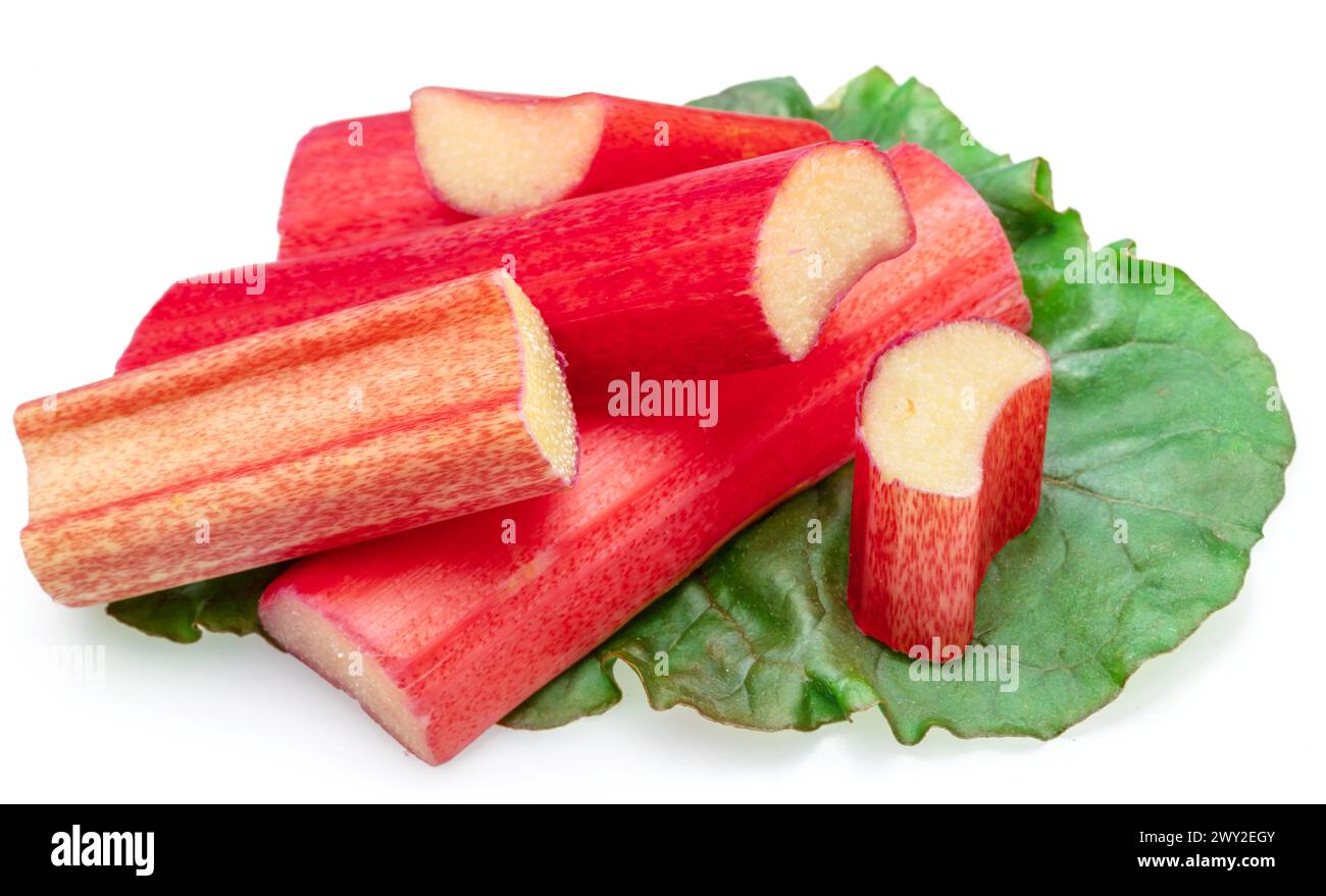 Red rhubarb stems' cuts over rhubarb leaves isolated on white background. Stock Photo