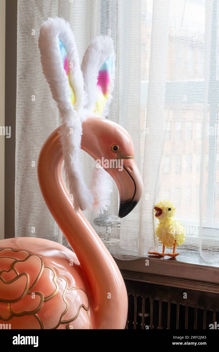 Humorous juxtaposition of a large pink flamingo statue, wearing rainbow