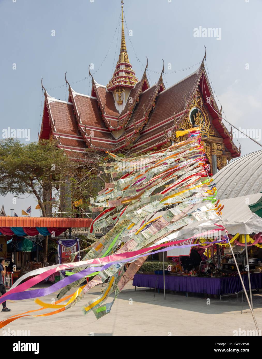 SAMUT PRAKAN, THAILAND, FEB 26 2024, Thai banknotes attached to a rope flutter in the wind in a Buddhist temple area Stock Photo