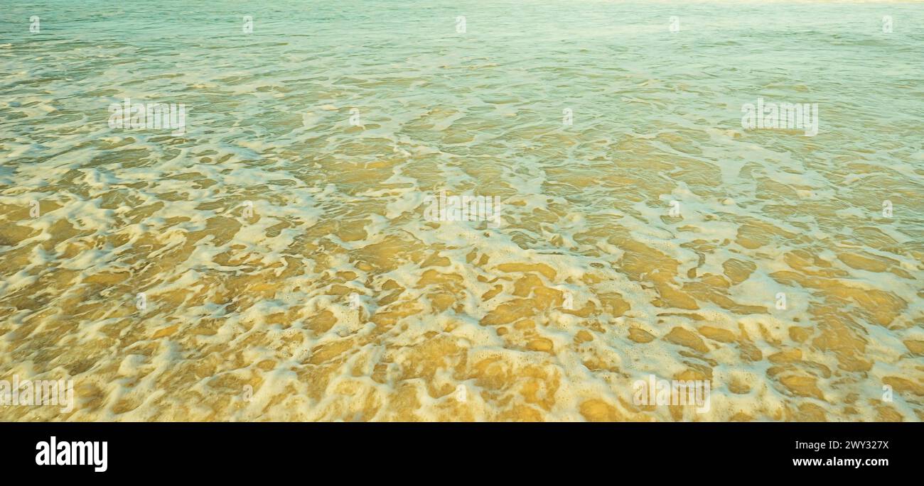 Ocean background of shallow sea water foaming and churning sand Stock Photo
