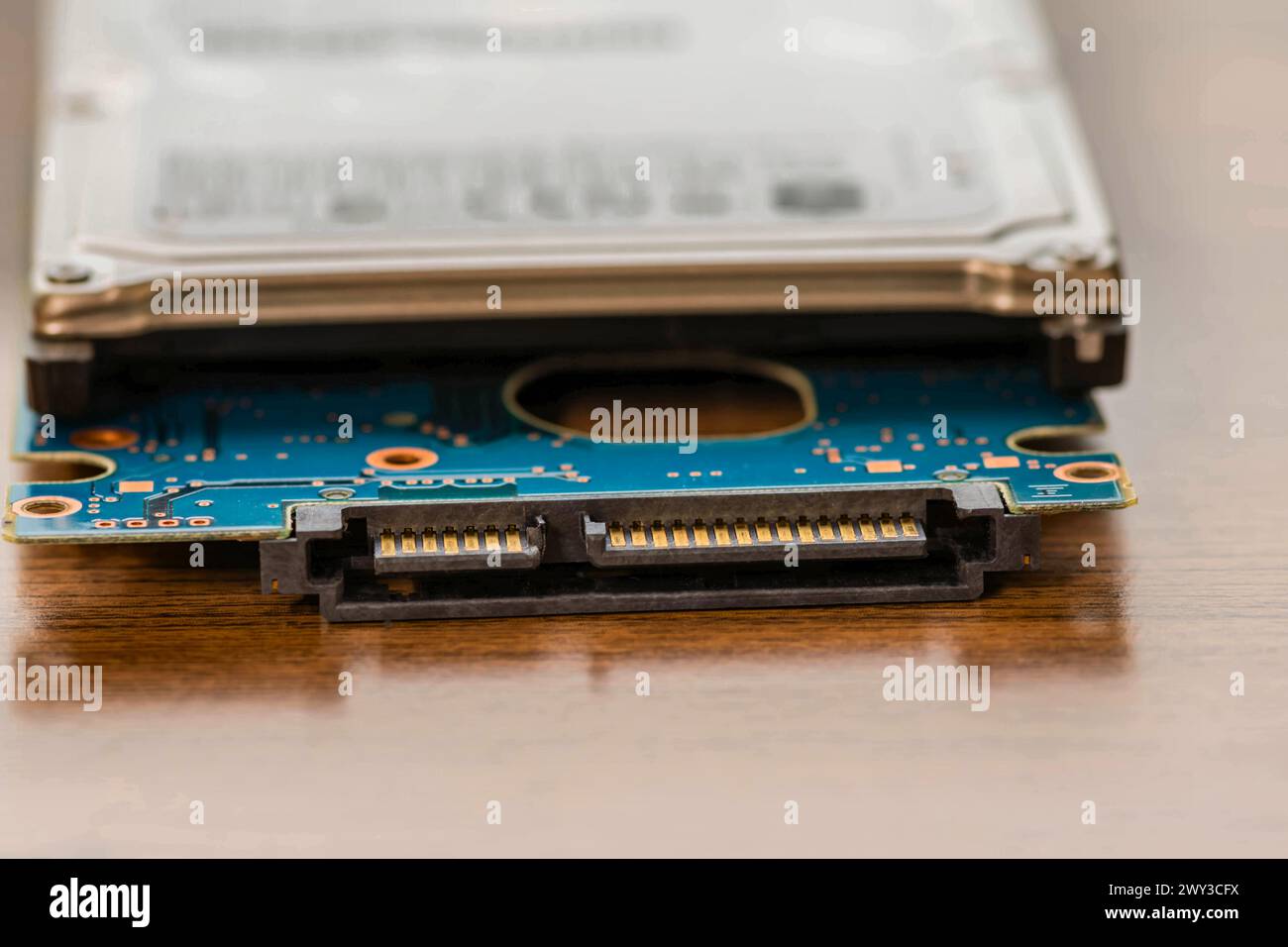Laptop computer hard drive with the circuit board removed and laying under disk case. SATA pins and circuitry clearly visible Stock Photo