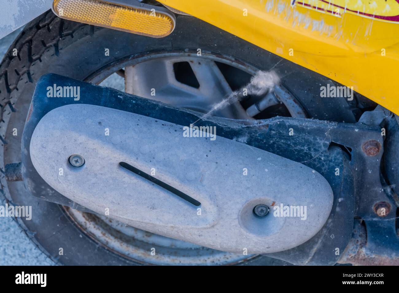 Exhaust and rear wheel and tire on parked yellow scooter in South Korea Stock Photo