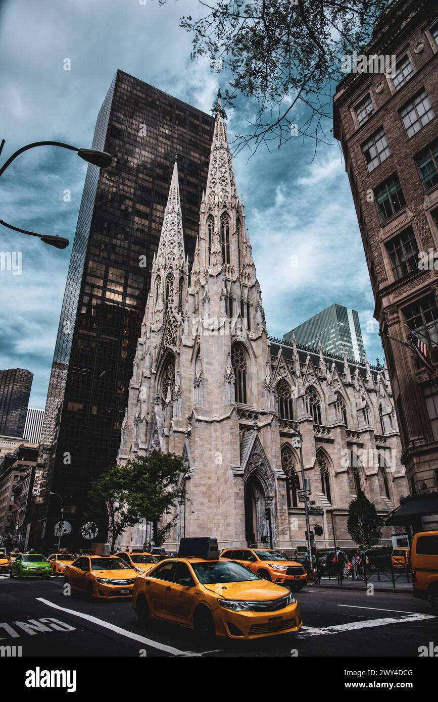 Yellow and Green Taxis passing by St. Patrick's Cathedral on Fifth Avenue - Manhattan, New York City Stock Photo