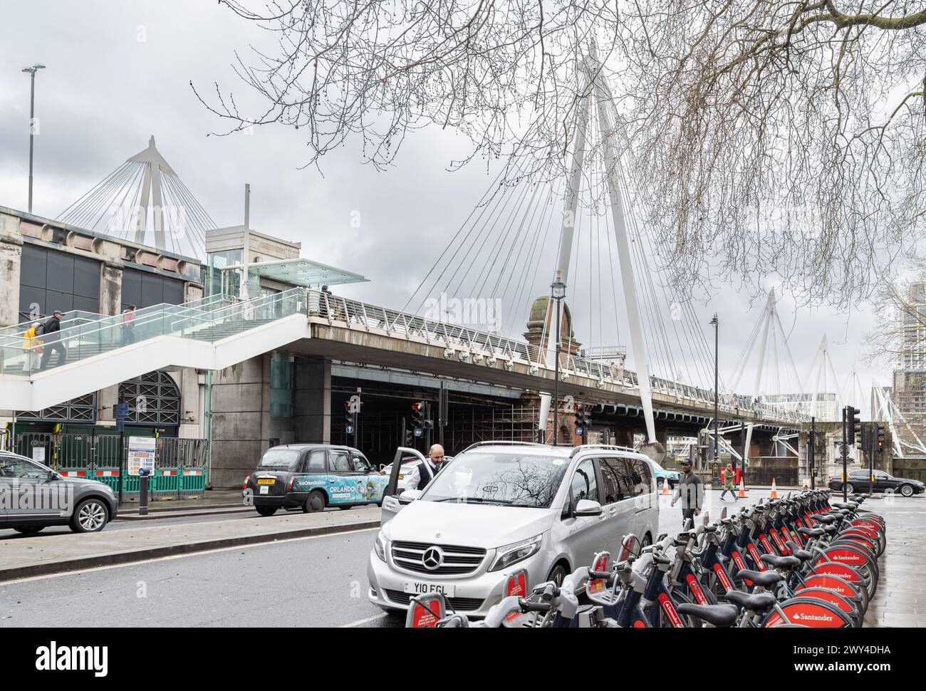 A view from the street of the Golden Jubilee Bridge as it crosses the River Thames. Pedestrians crossing the Thames on the Golden Jubilee Bridge. Stock Photo