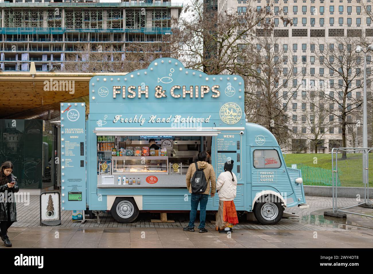 Customers waiting for their food at a mobile fish and chips van selling 100% halal meals in London. Travel, culture, small business or diet concept. Stock Photo