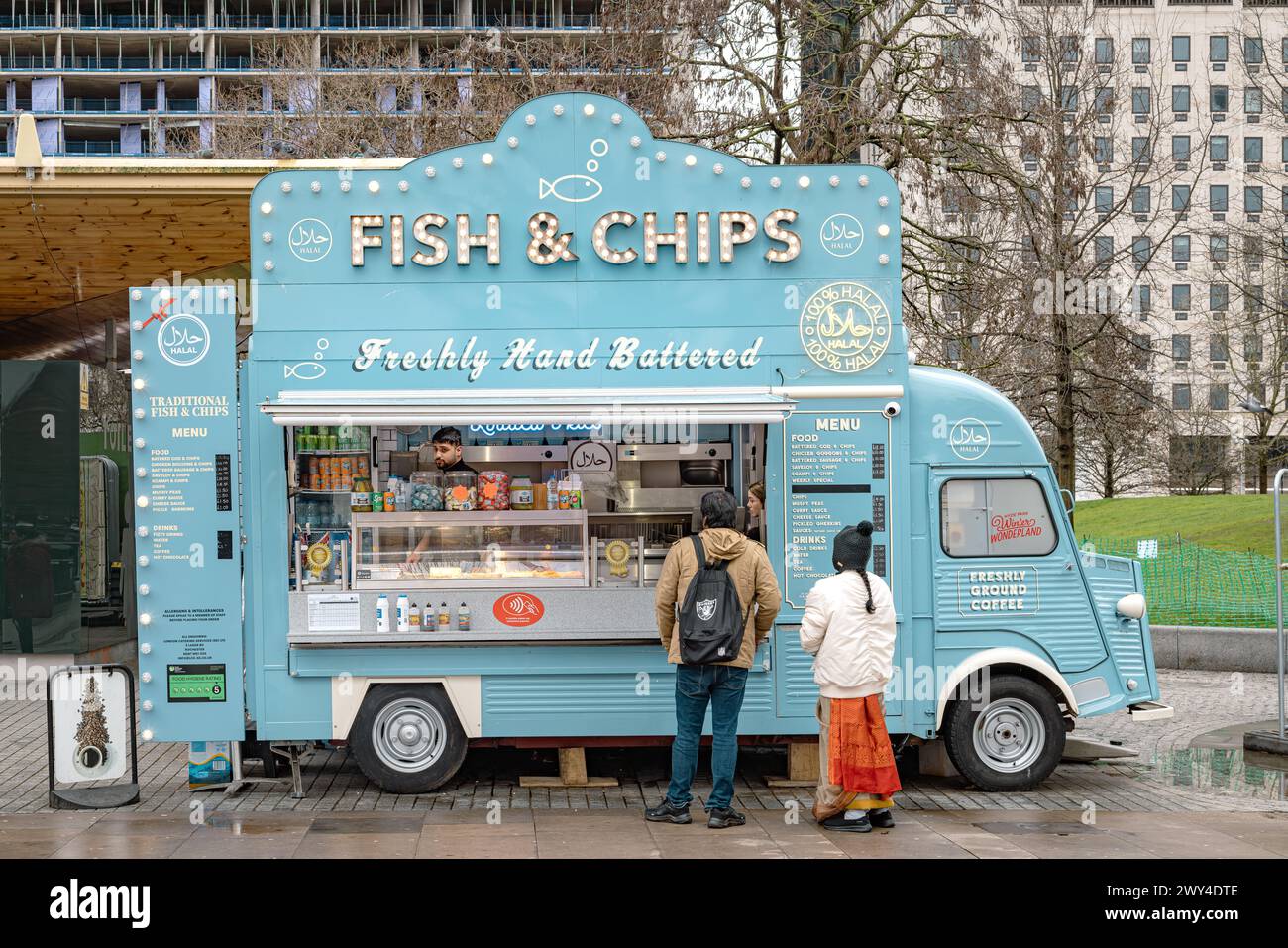 Customers waiting for their food at a mobile fish and chips van selling 100% halal meals in London. Travel, culture, small business or diet concept. Stock Photo