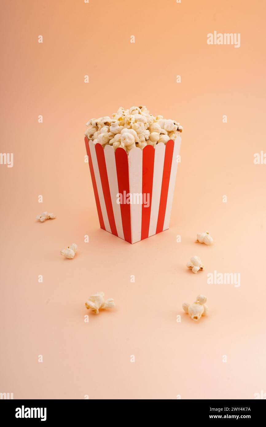 A striped popcorn bucket on a tan background. Stock Photo