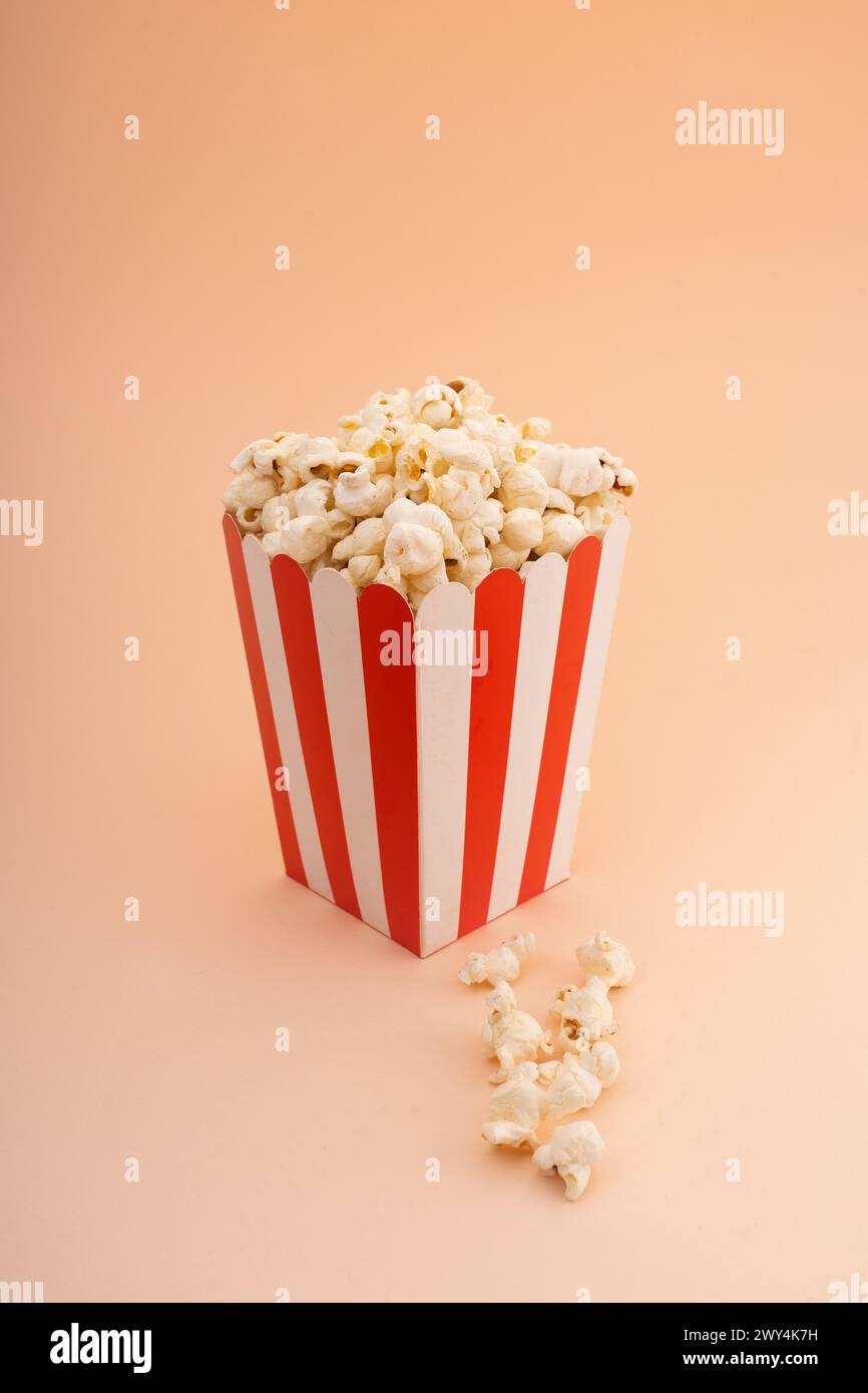 A striped popcorn bucket on a tan background. Stock Photo