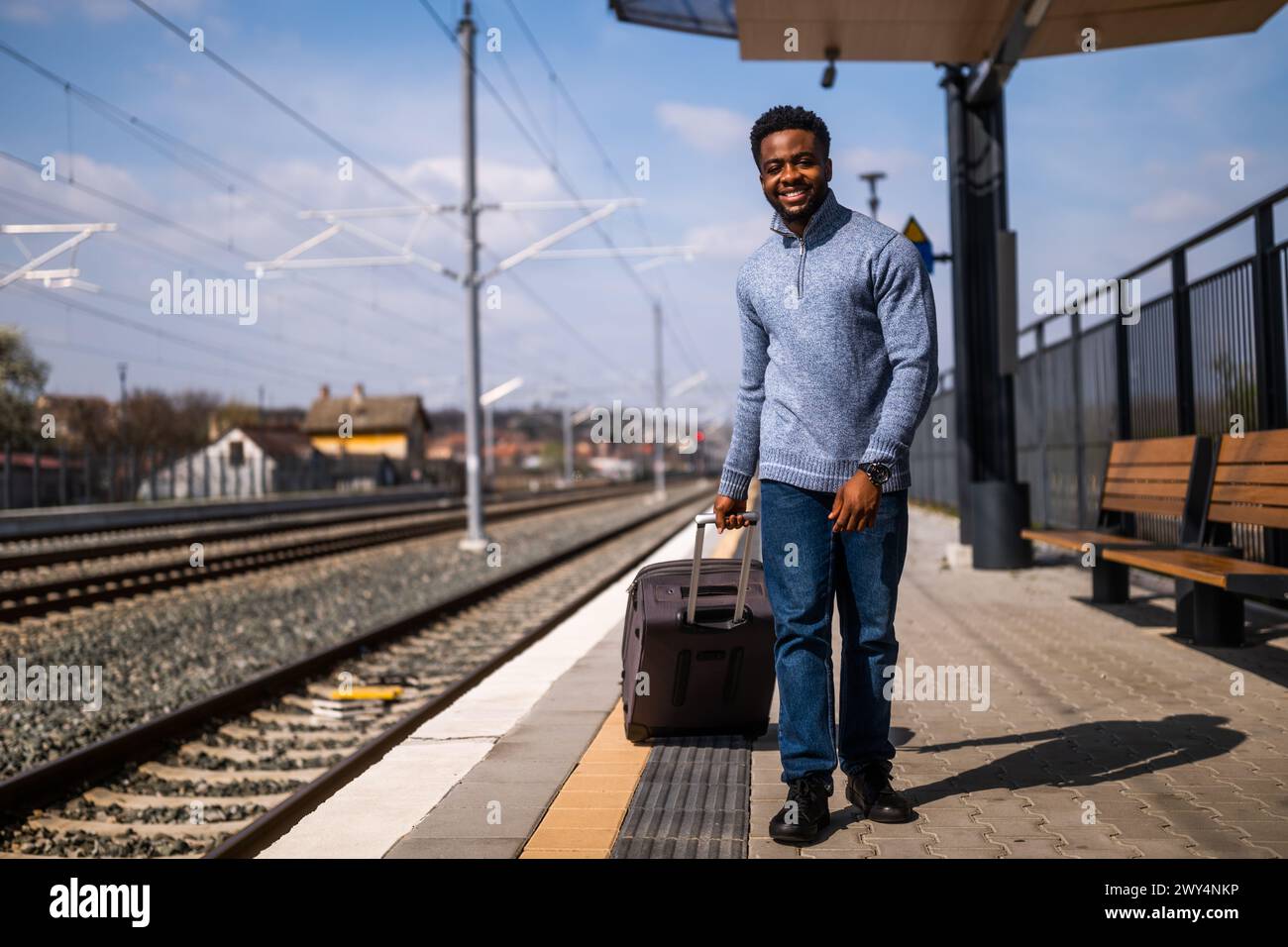 Happy man with suitcase walking on railway station. Stock Photo