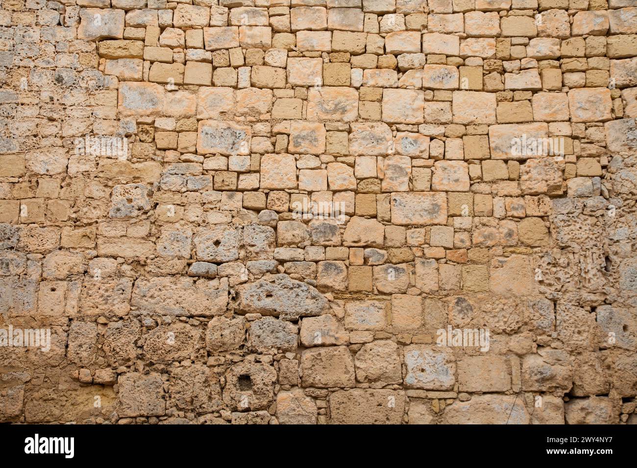 Old limestone wall irregular bricks stones textured background. Stock Photo