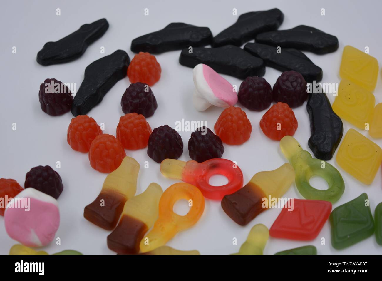 Candies in the form of a black car, raspberries, blackberries, cola bottles, colored keys, diamonds with the alphabet. Stock Photo