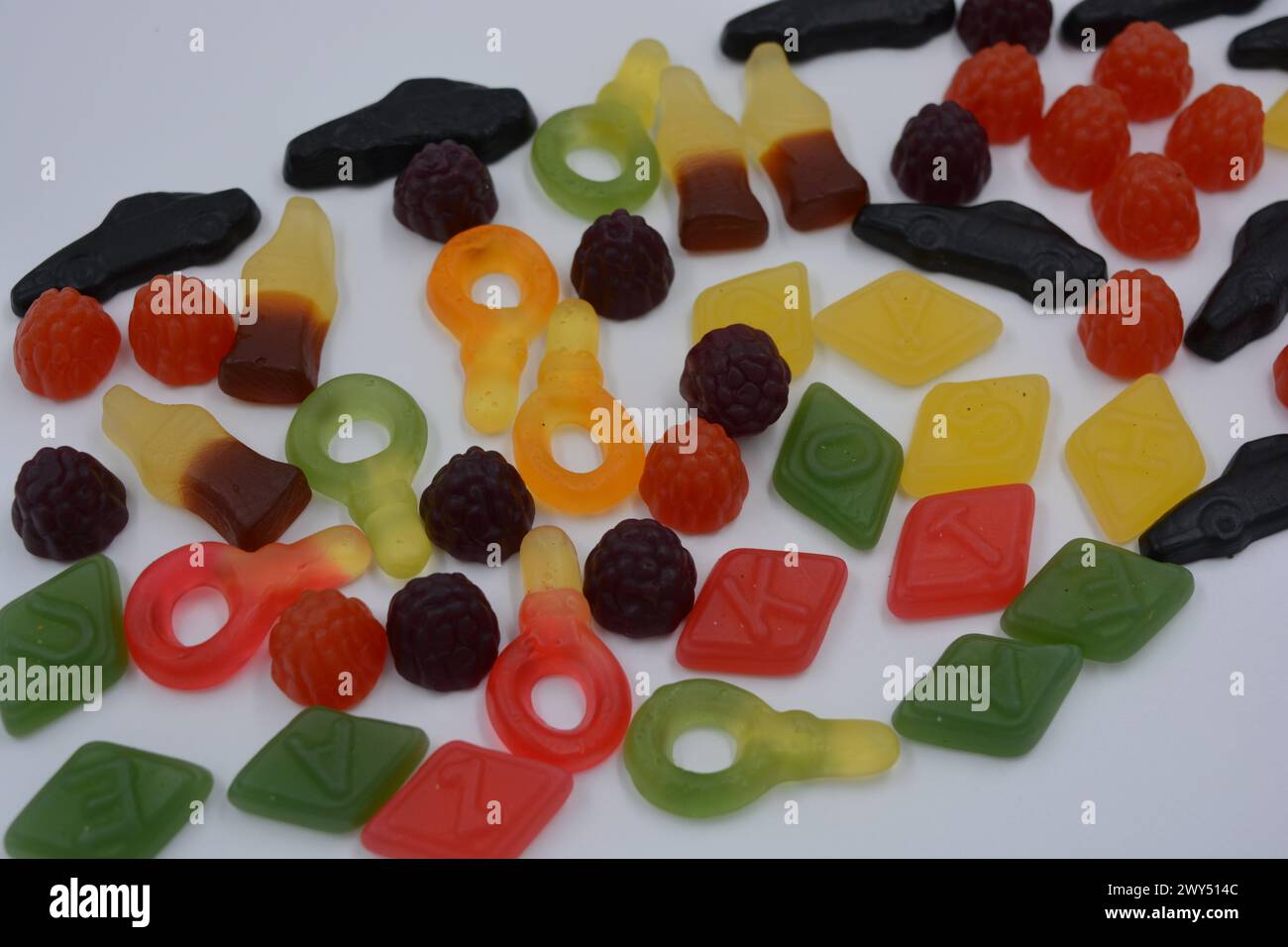 Candies in the form of a black car, raspberries, blackberries, cola bottles, colored keys, diamonds with the alphabet. Stock Photo