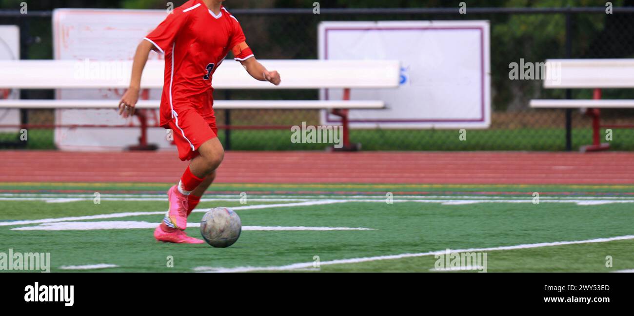 One soccer player dribbling the ball down the field during a game at a high school. Stock Photo