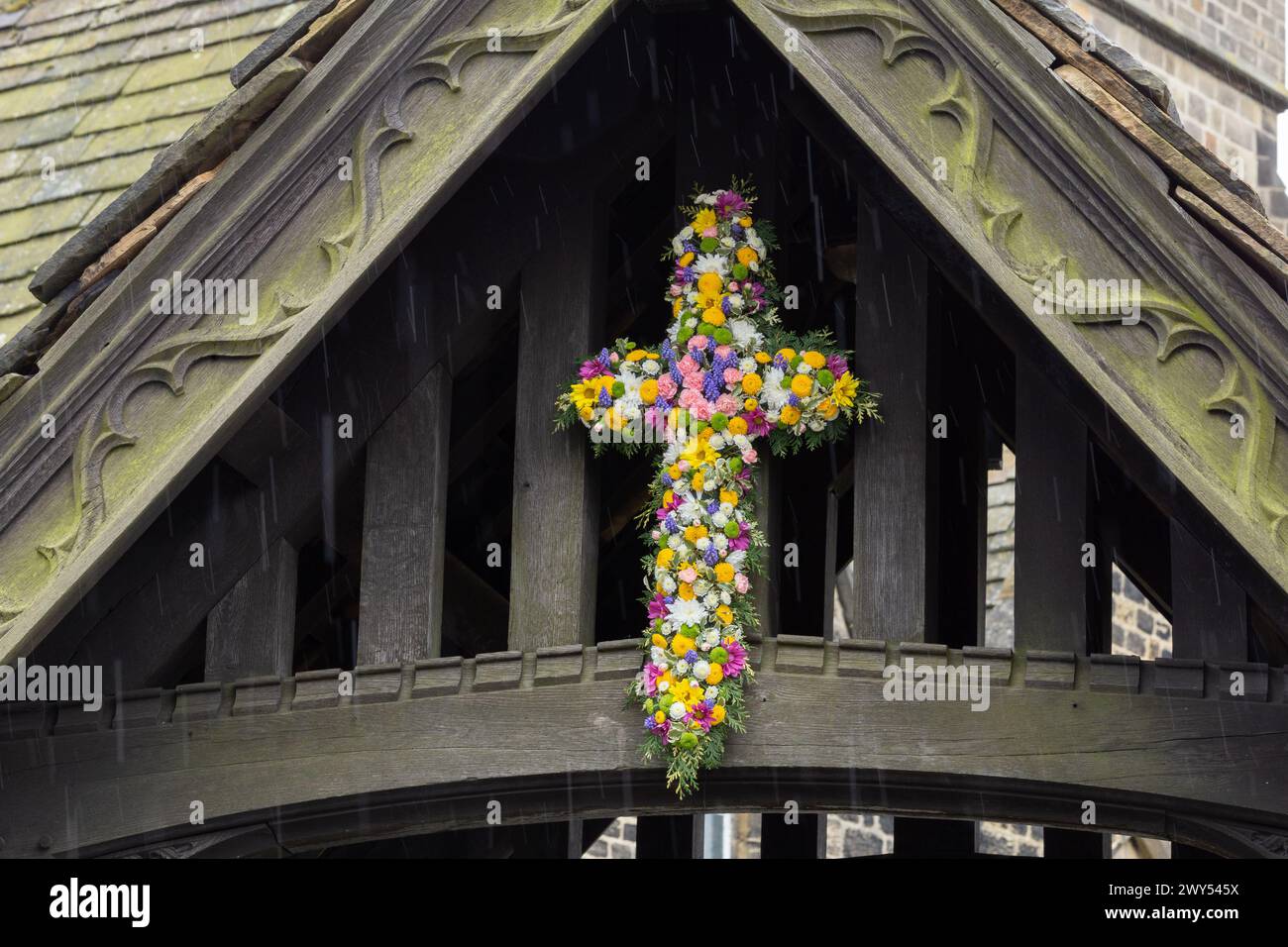 A floral Easter Cross above the lychgate at St John's Church of England in Baildon, Yorkshire, England. This is known as 'Flowering the Cross'. Stock Photo