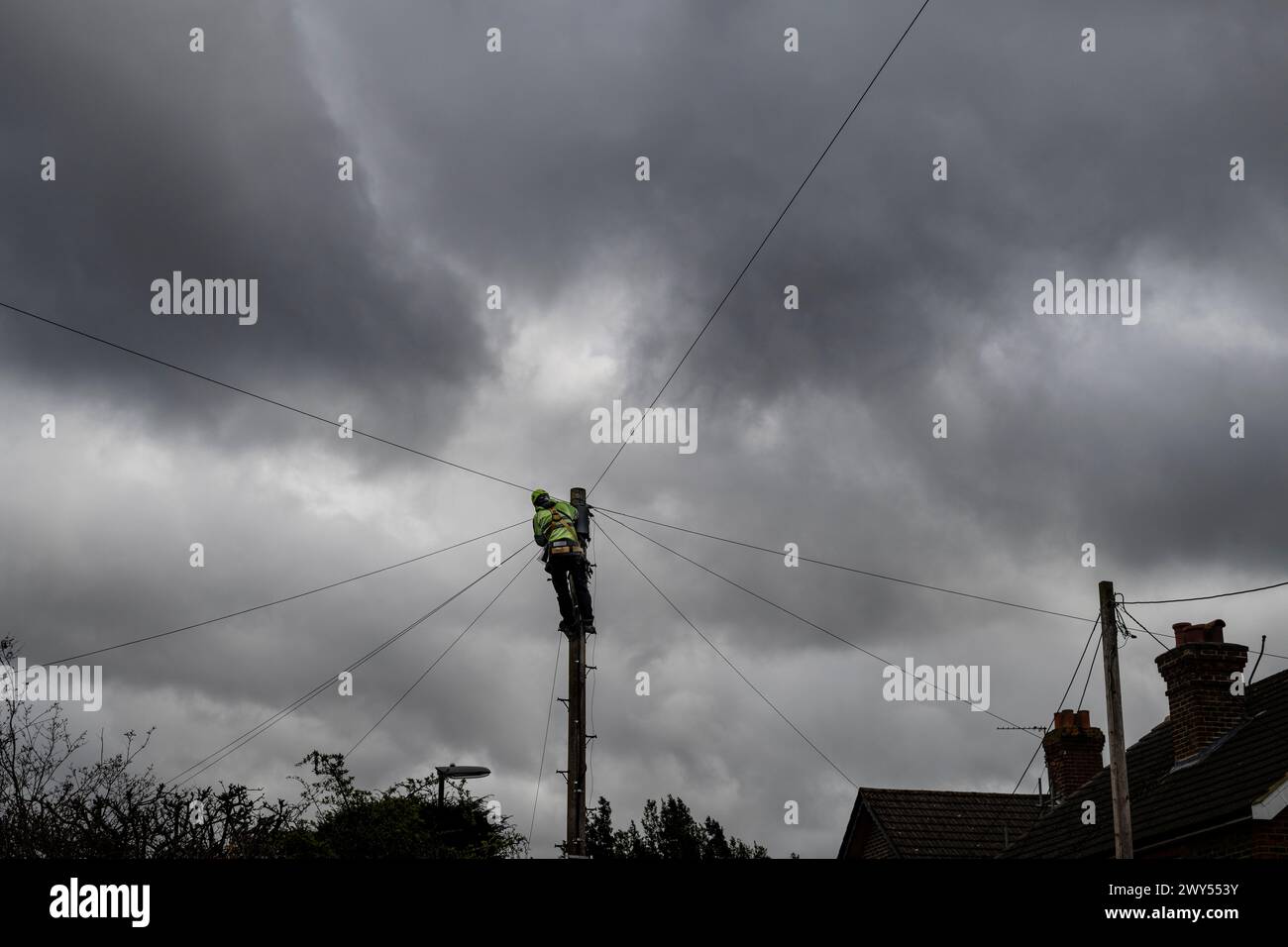Worker, strapped onto Telegraph poll working on communication cables Stock Photo
