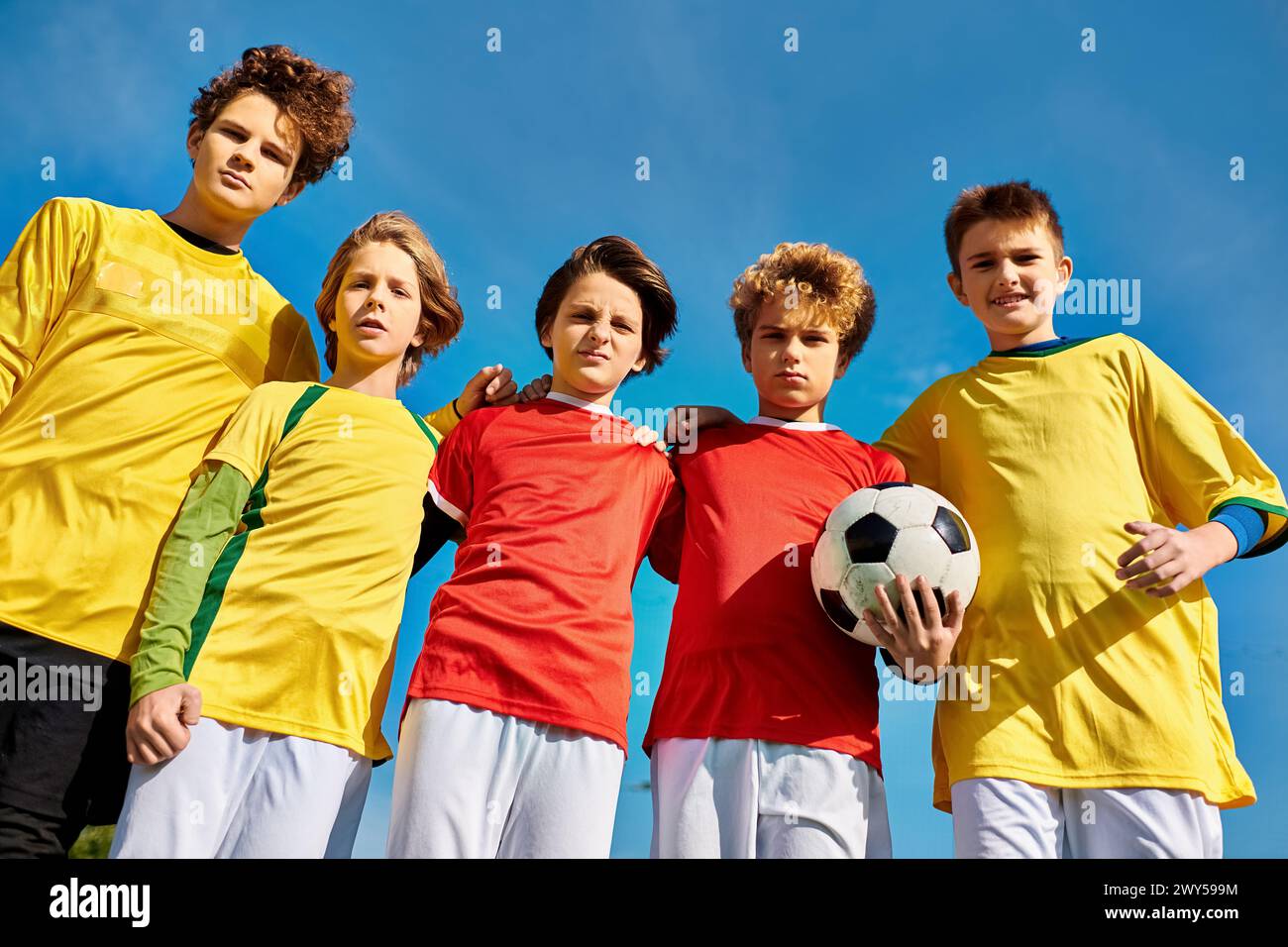 A group of young men standing closely together, holding a soccer ball, showcasing teamwork and camaraderie. Stock Photo