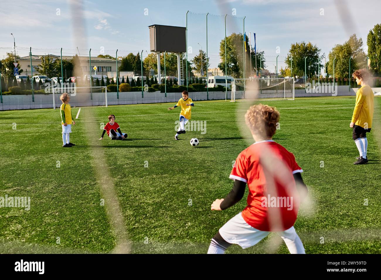 A group of young children are playing an energetic game of soccer on a grassy field. They are running, passing, and kicking the ball with excitement a Stock Photo