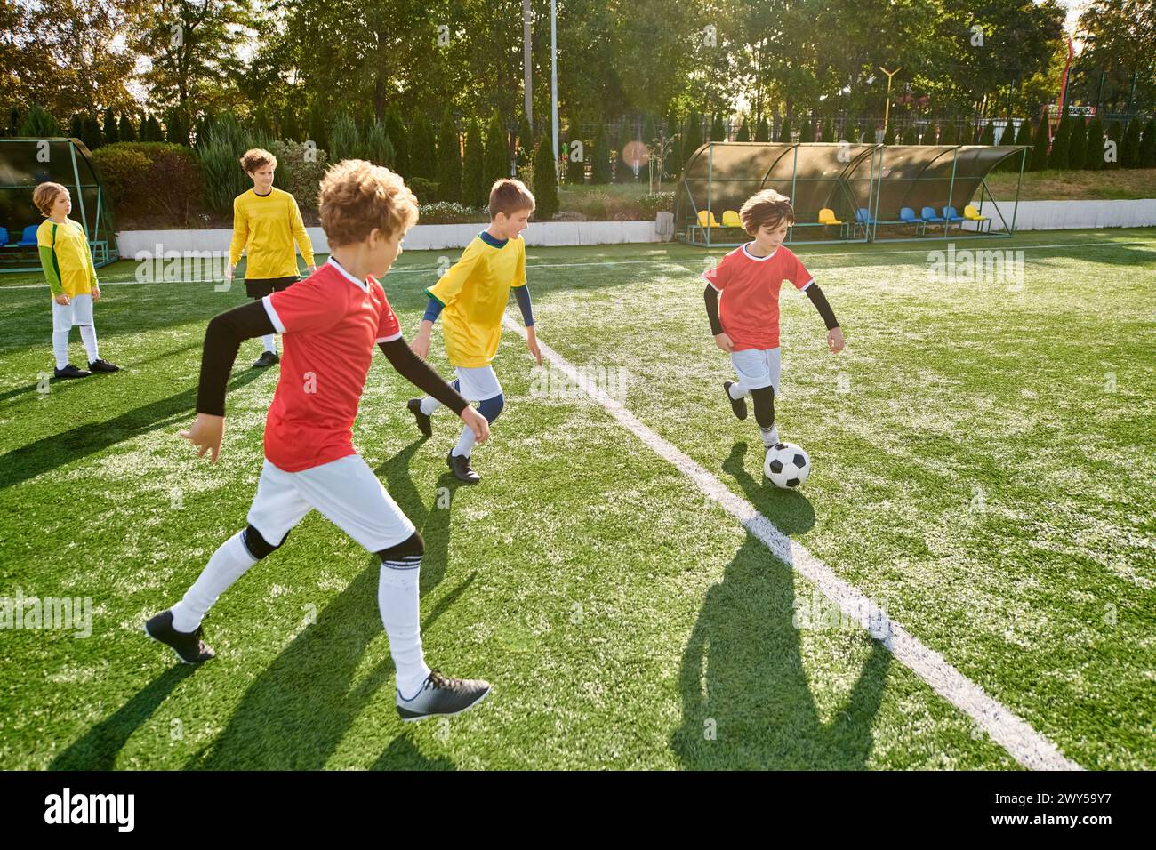 A group of young boys enthusiastically playing a game of soccer on a green field. They are running, kicking the ball, and cheering each other on, disp Stock Photo