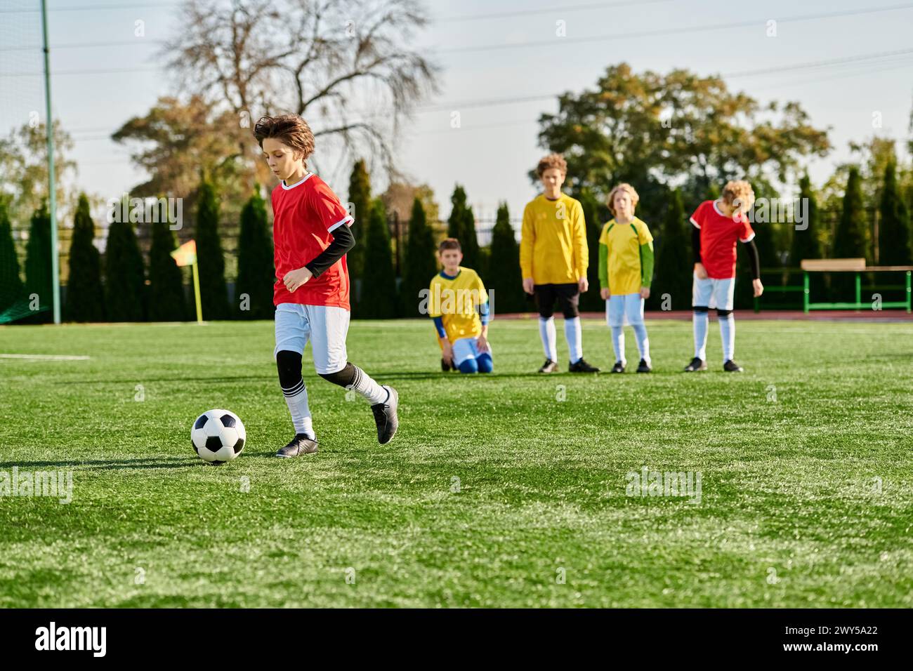 A group of young children, filled with joy and enthusiasm, are engaged in a spirited game of soccer. They are running, kicking, and passing the ball, Stock Photo
