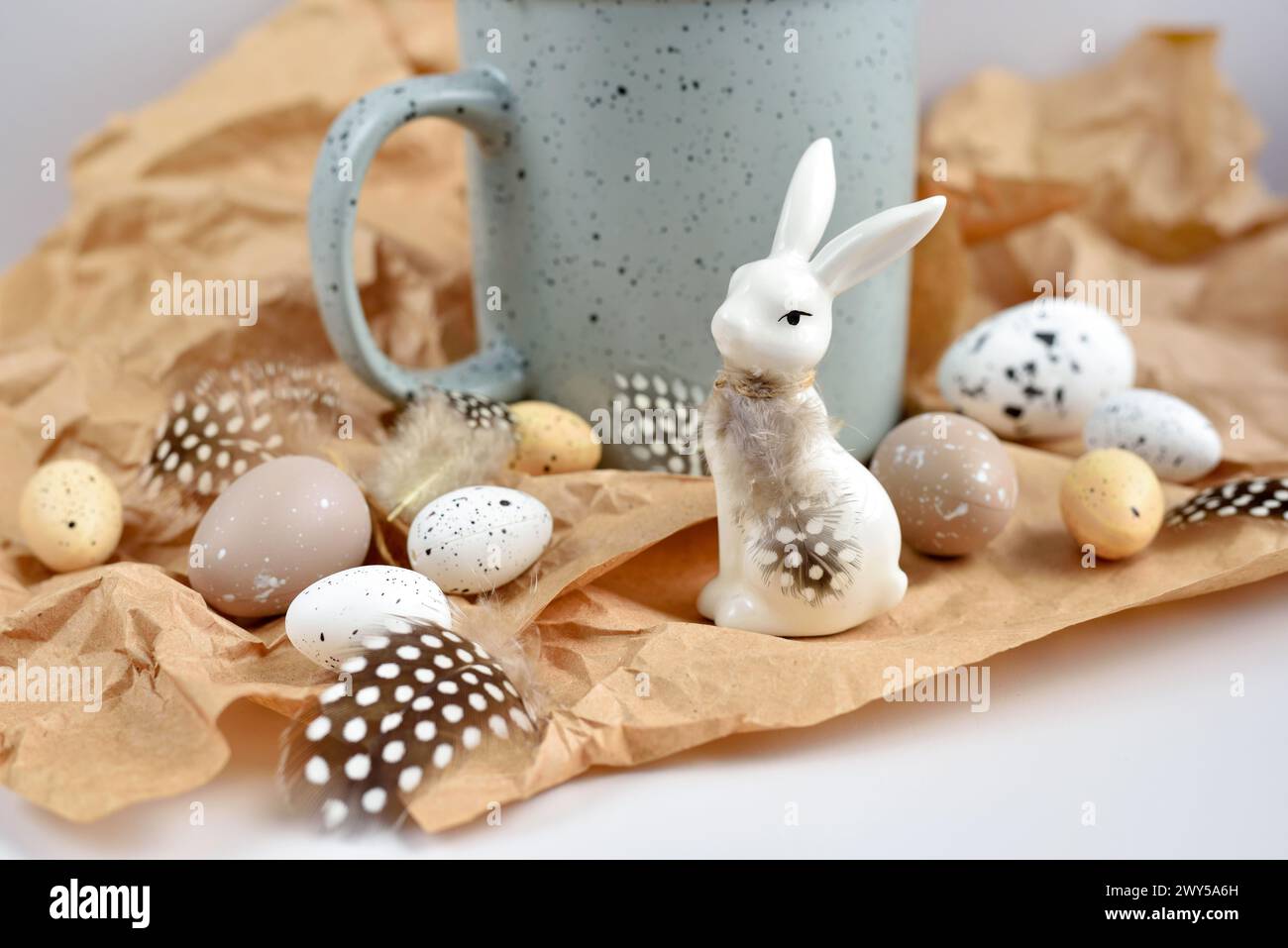 Easter composition with white rabbit, eggs and feathers on a brown kraft paper background. Easter still life Stock Photo