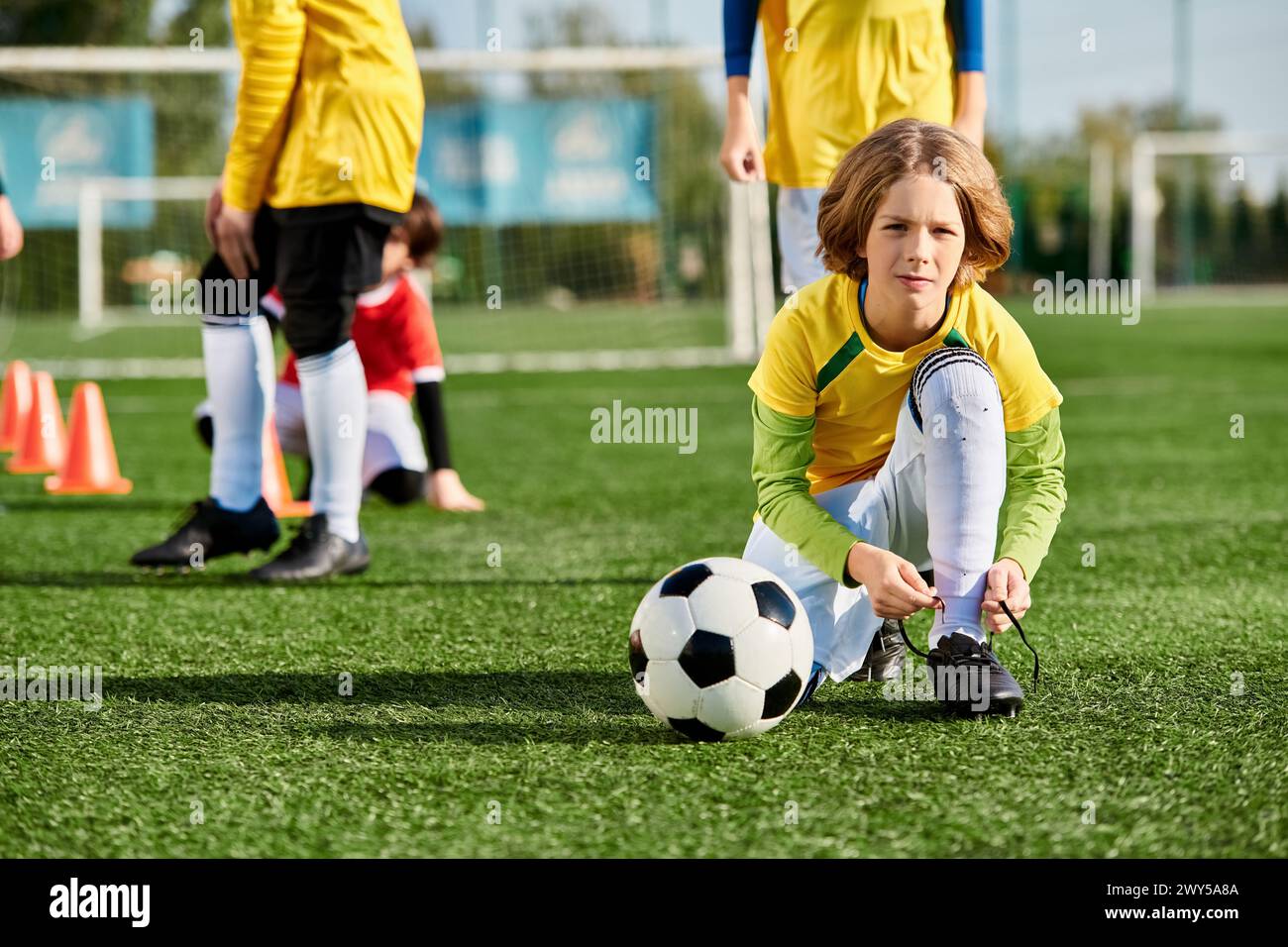 A young girl energetically plays soccer on a field, confidently dribbling the ball and aiming for the goal. Her eyes are filled with determination as Stock Photo