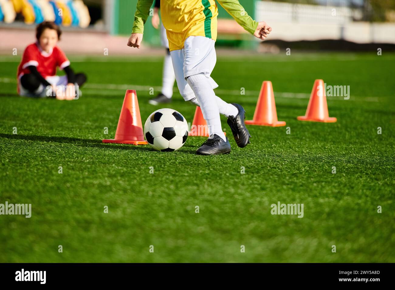 A determined young boy practices dribbling a soccer ball around cones