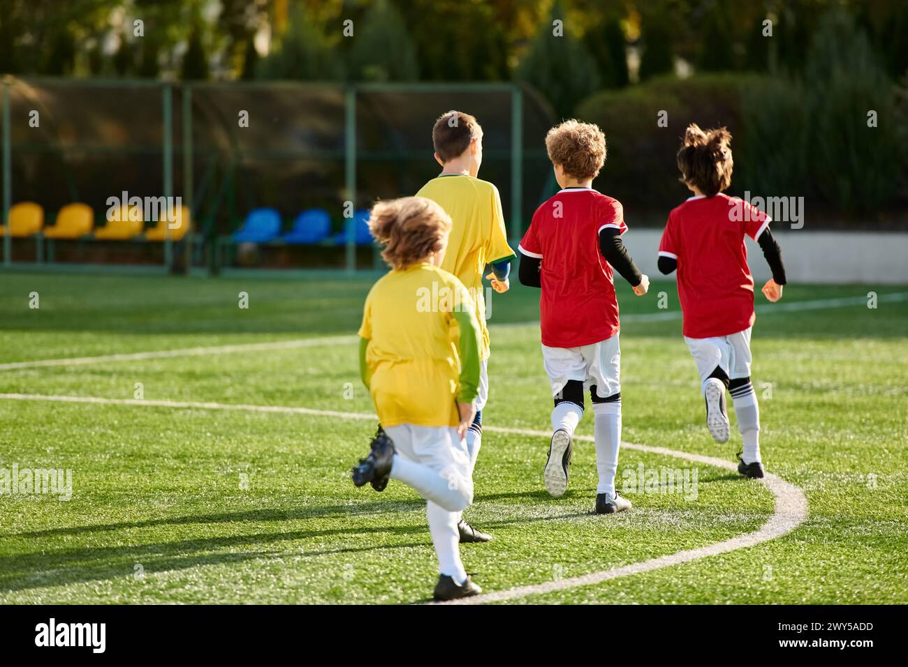 A lively scene of children playing a spirited game of soccer, running, kicking, and cheering on the grassy field with enthusiasm and excitement. Stock Photo