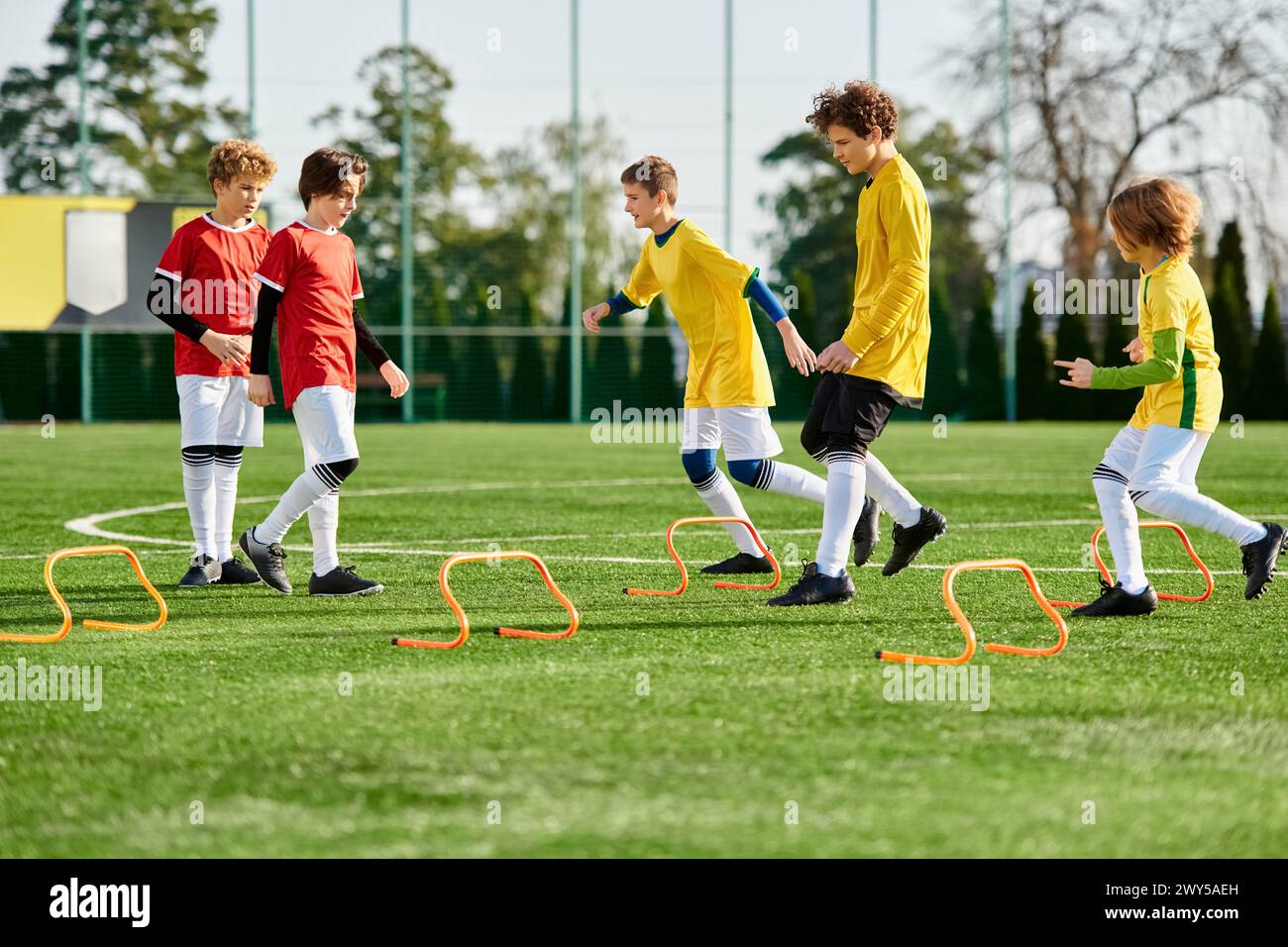 A lively group of young boys engage in a spirited game of soccer, kicking the ball across the field with enthusiasm and skill. Laughter fills the air Stock Photo