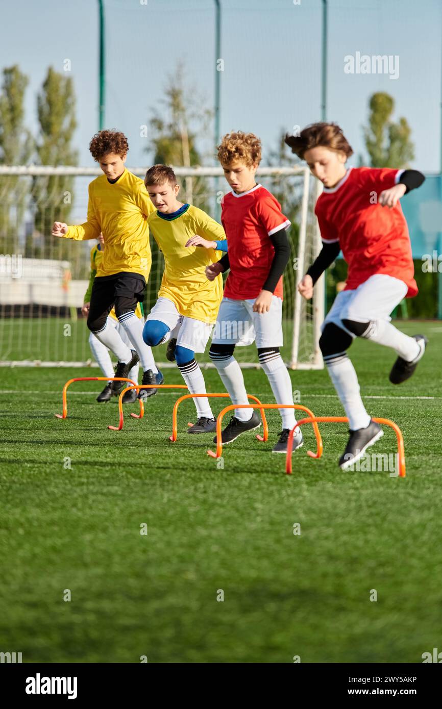 A group of young boys playing an energetic game of soccer on a grassy field. They are running, kicking the ball, and cheering each other on as they co Stock Photo