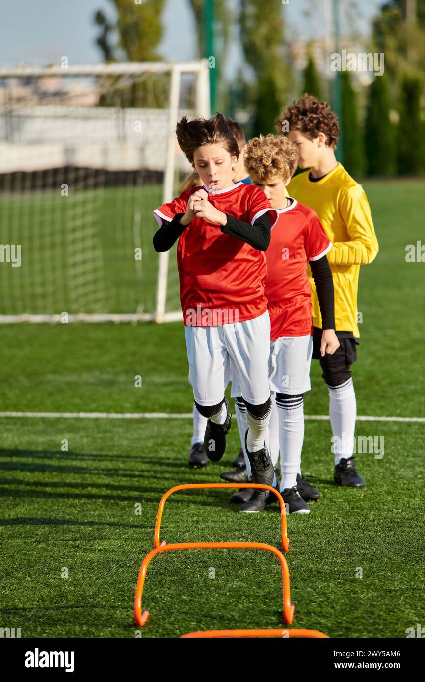 A diverse group of young boys energetically stand at the top of a vibrant soccer field, showcasing their teamwork and camaraderie as they prepare to p Stock Photo