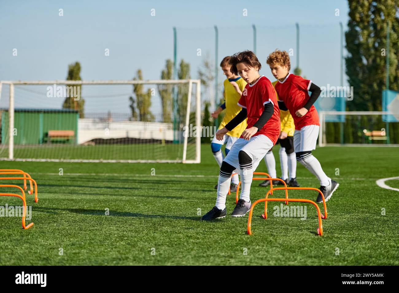 A group of energetic young boys playing a game of soccer in a grassy field, kicking the ball, running, and laughing together as they compete in a frie Stock Photo