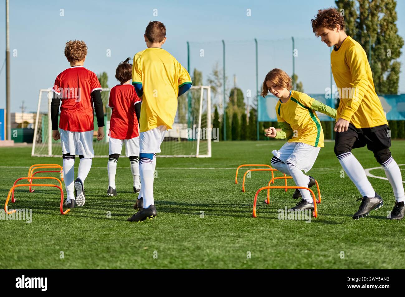 A group of young boys are energetically playing a game of soccer on a grassy field. They are running, kicking the ball, and cheering each other on in Stock Photo