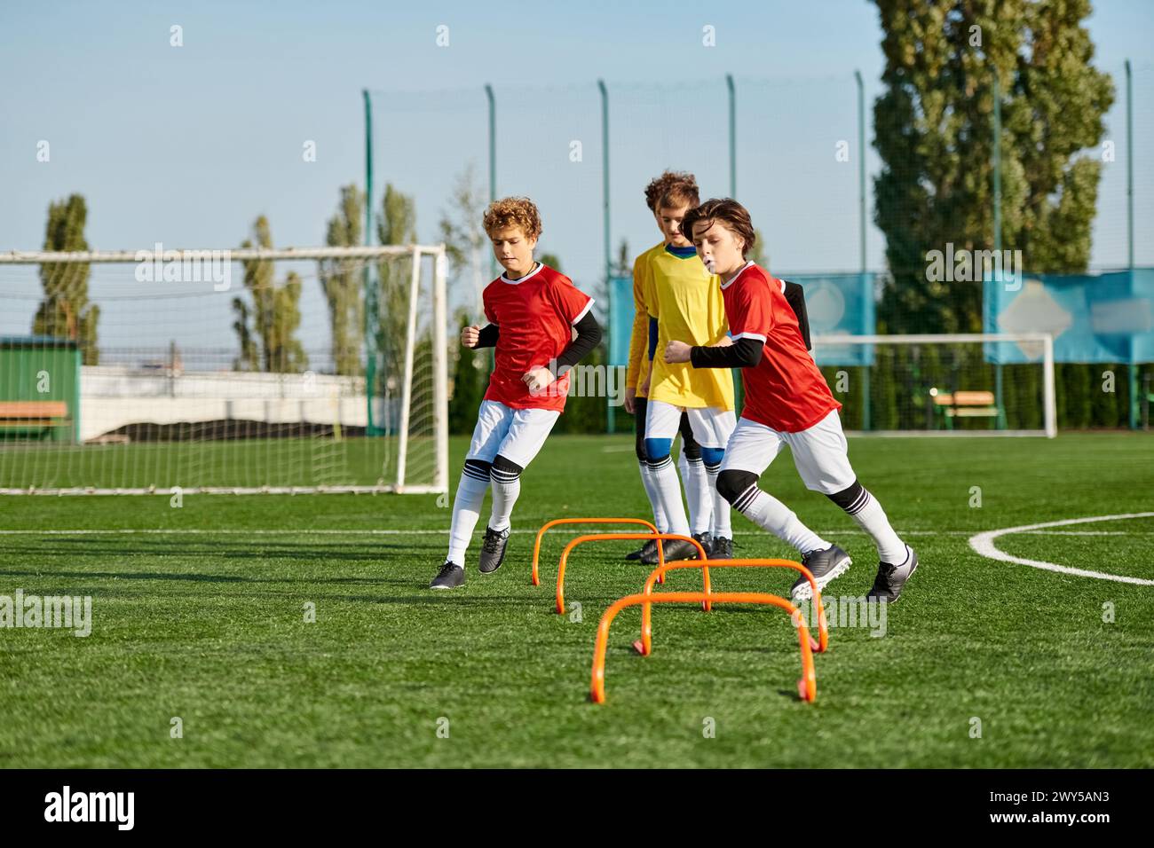 A group of young boys enthusiastically playing a game of soccer, kicking the ball back and forth, sprinting across the field, and joyfully celebrating Stock Photo