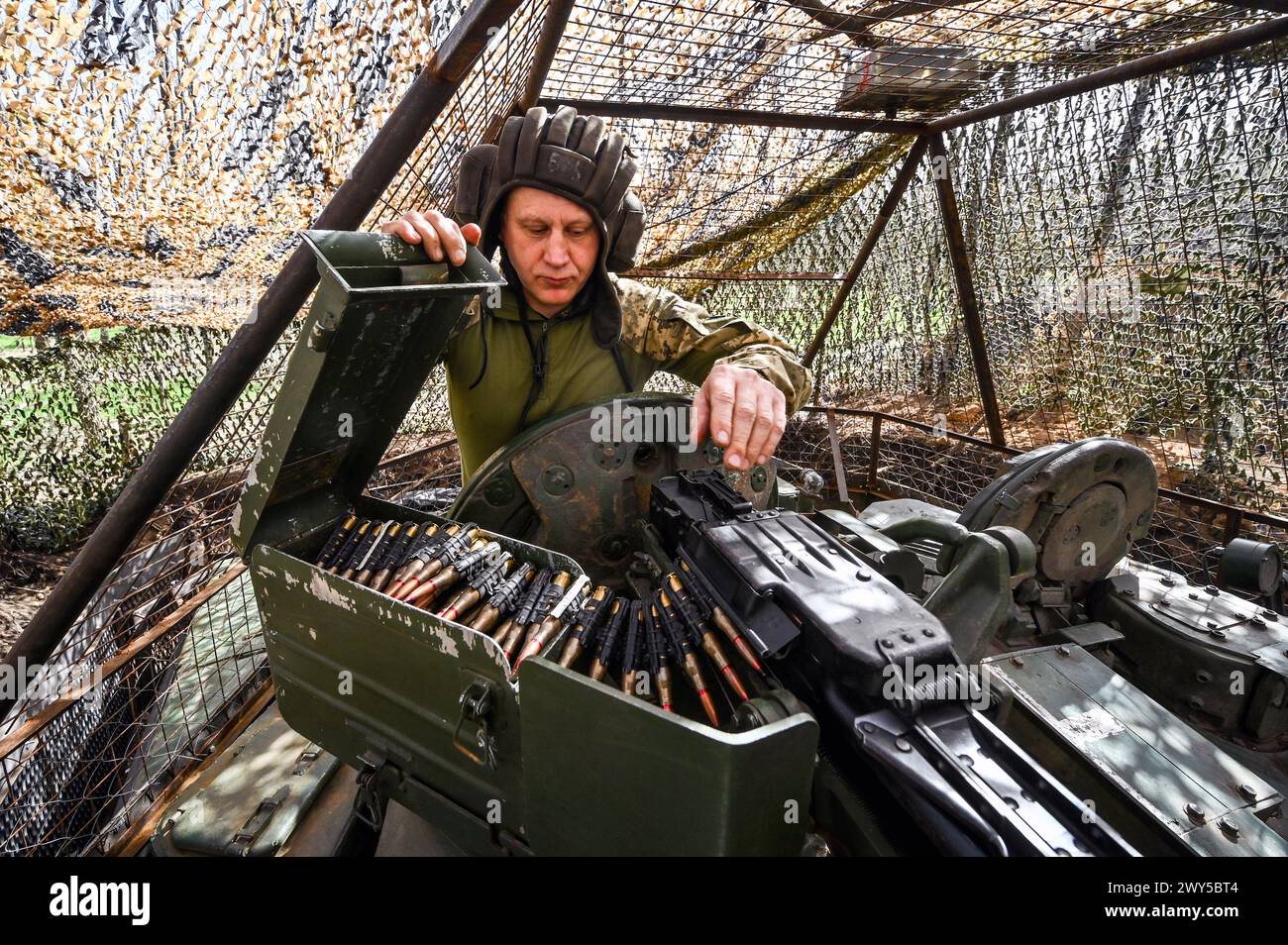 UKRAINE - MARCH 31, 2024 - A serviceman of the 1st Tank Brigade of the Ukrainian Ground Force shows an ammunition belt on a tank, Ukraine. Stock Photo